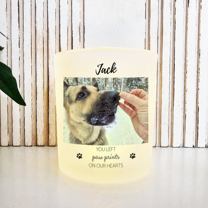 The Little Piece Candle Co. Personalized Remembrance Pet Memorial Candle displays a photo of a German Shepherd with "Jack" above and "You left paw prints on our hearts" below, plus paw print icons, on an LED tea light holder for dogs, cats, or pets.
